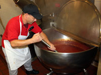 Cook stirring a large pot of sauce