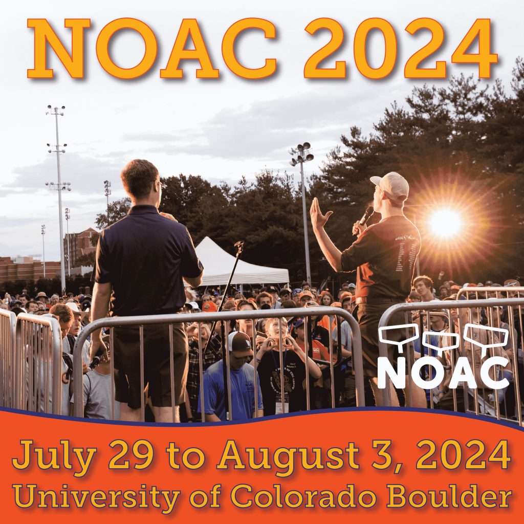 Orange and gold promotional image for NOAC 2024 event, taking place from July 29 to August 3, 2024, at the University of Colorado Boulder. The image features a back view of two people addressing a crowd of attendees who are cheering and raising their hands. A setting sun is visible in the background, casting a warm glow over the event.